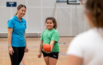 Stirling Leisure employee teaching a child how to pass a rugby ball